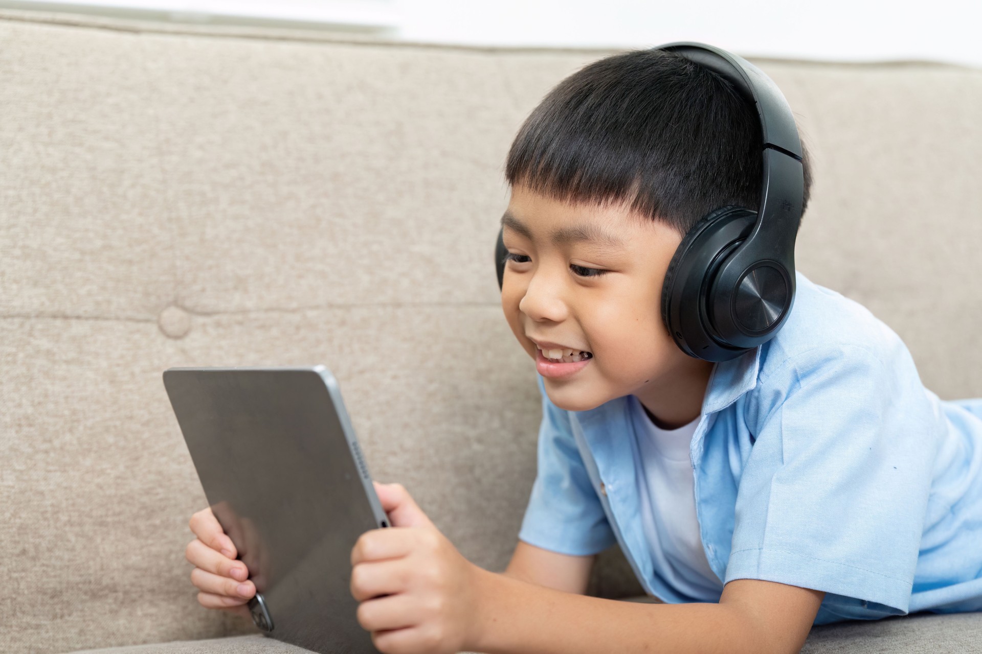 Back to School and Family Bonding. A young boy engaged with a tablet, enjoying educational content at home.