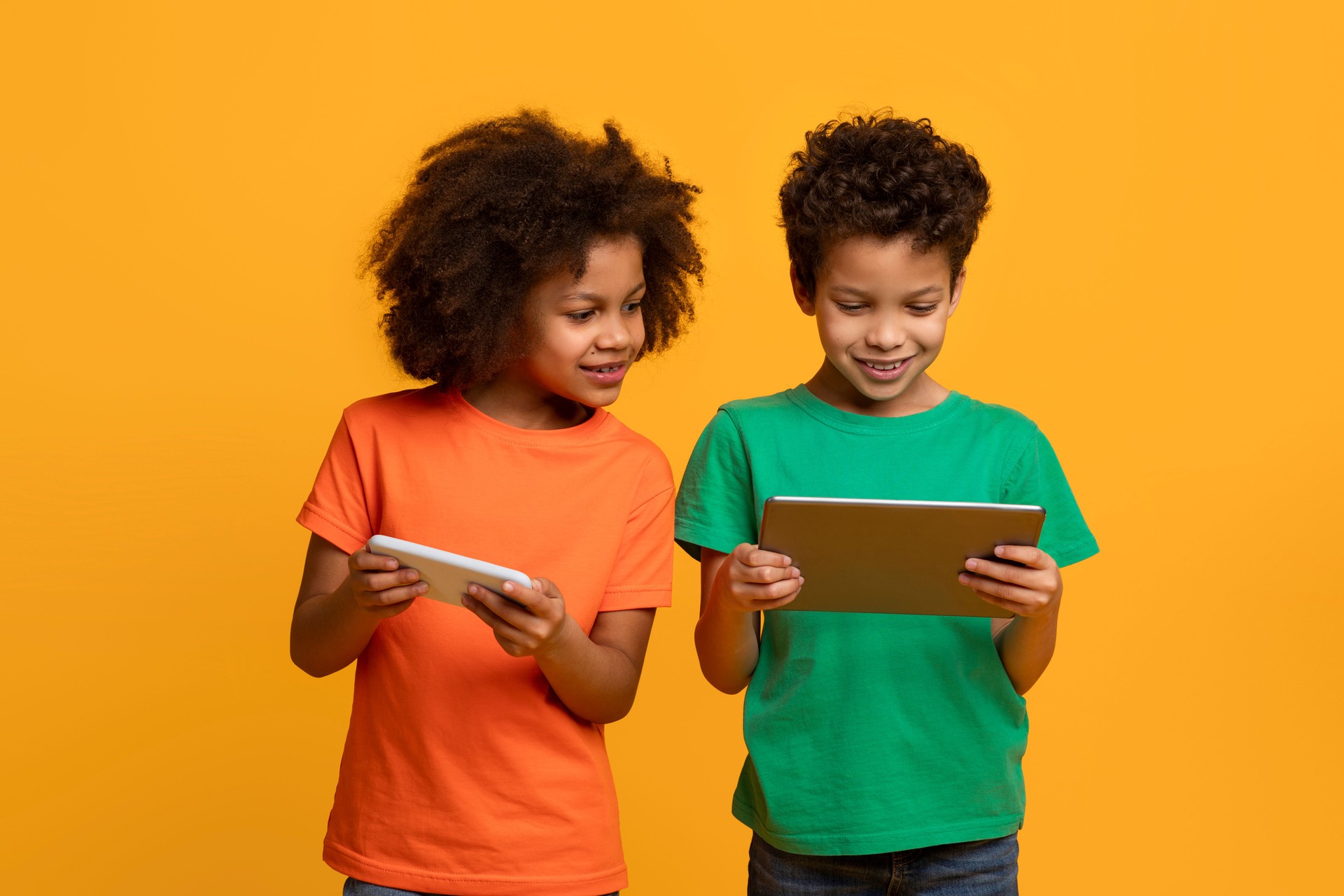 Two Young Children Standing Looking at a Tablet